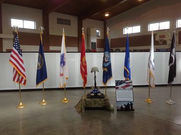 A military memorial display with flags, a helmet, boots, and a folded American flag.
