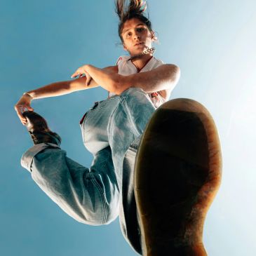 Person jumping with one leg bent, shoe sole facing camera.