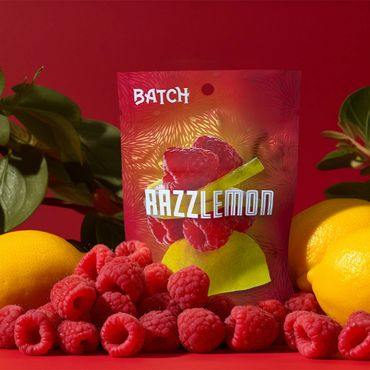 Razzlemon candy packaging surrounded by fresh raspberries and lemons.