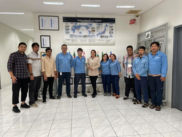 A group of colleagues posing indoors in front of a world map and flags.