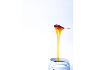 Golden honey dripping from a spoon into a jar.