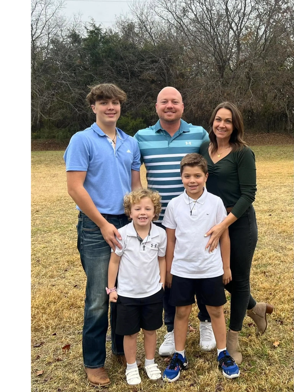 A smiling family of five posing outdoors in casual clothes.