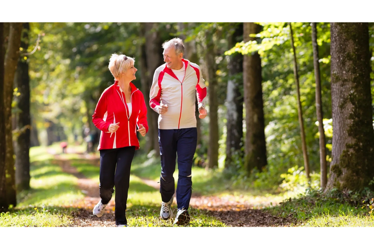 two adults smiling and outside jogging in the woods