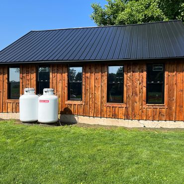 Wooden building with propane tanks on grass.