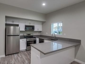 Modern kitchen with stainless steel appliances and grey countertops.