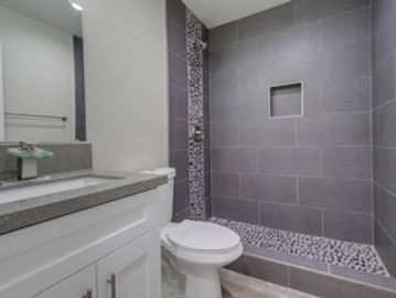 Modern bathroom with grey tiles and a white vanity.