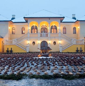 A grand mansion courtyard with many hunted animals arranged in circles around a boar statue.