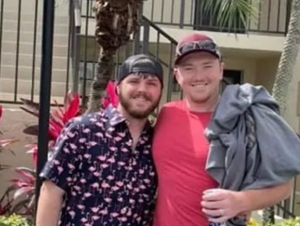 Two men smiling outdoors, one in a flamingo shirt and the other in a red shirt.
