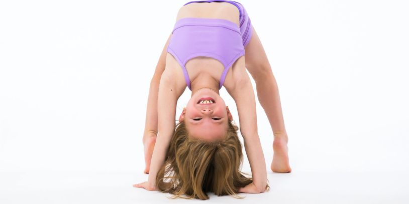 Young girl stretching in a purple outfit.