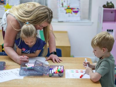 An educator helps a preschool age child with their curriculum.