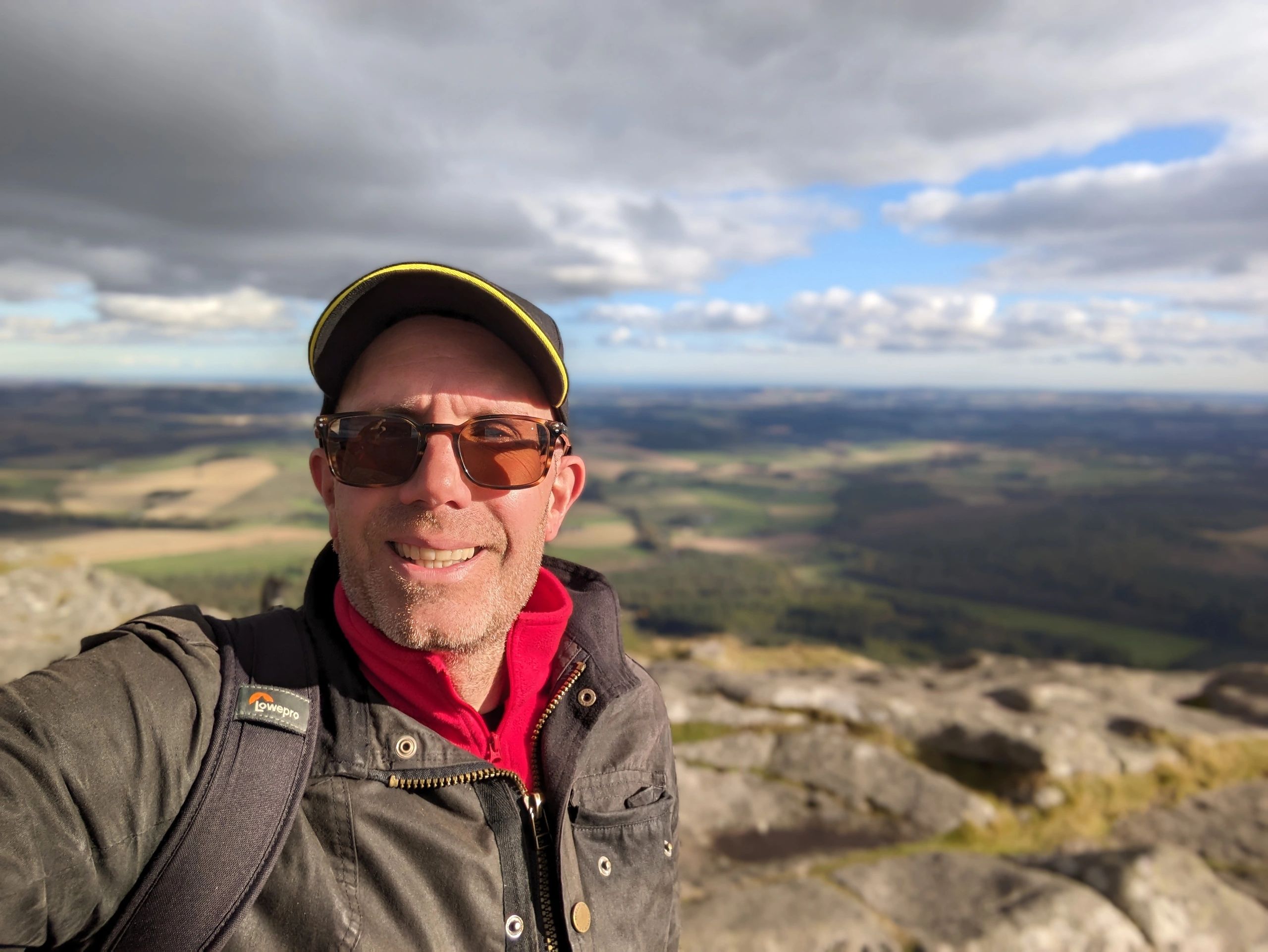 Filmaker taking a photo on a hilltop overlooking an Aberdeenshire landscape during a film project.