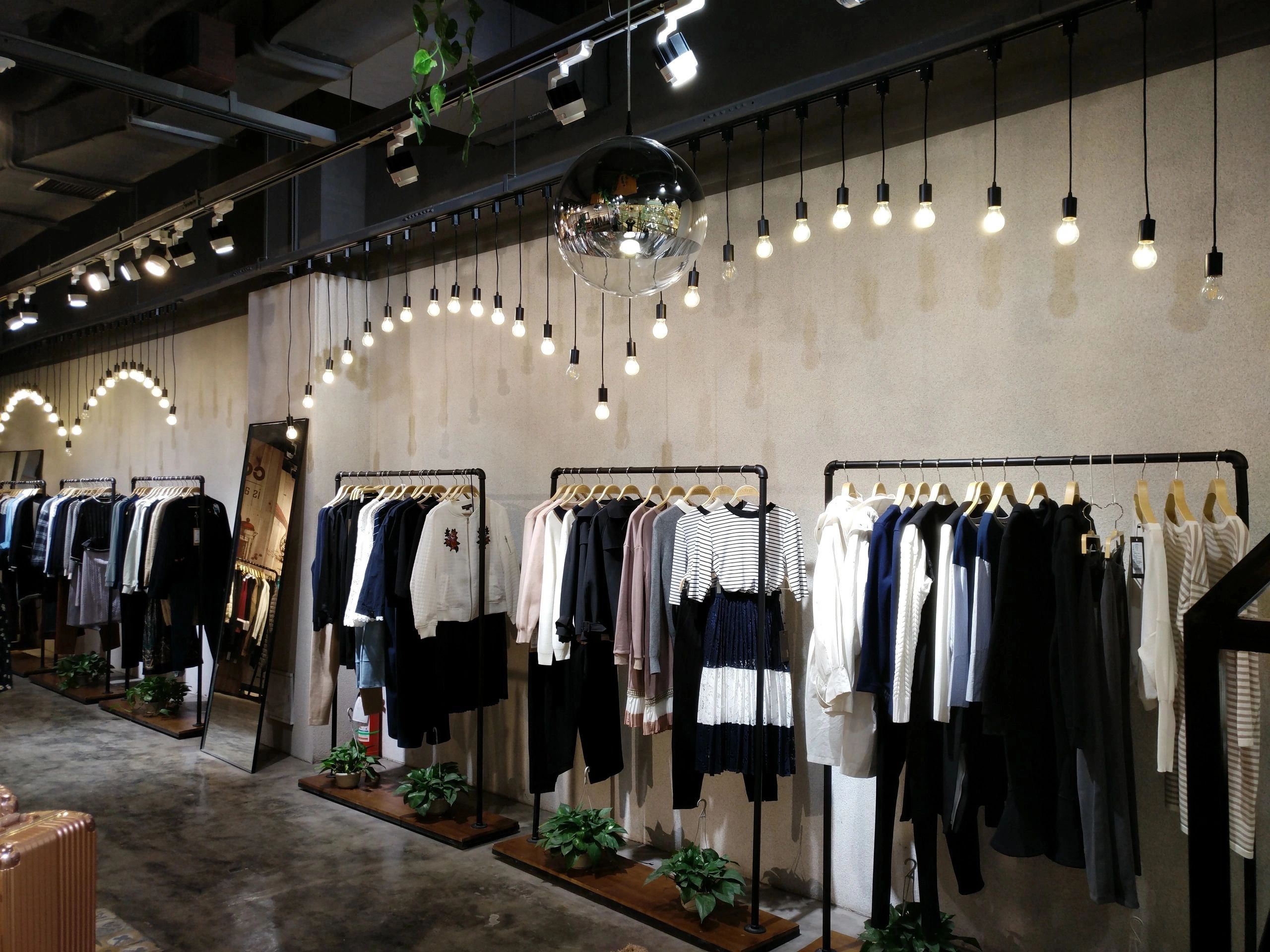 Clothing store with hanging light bulbs and racks of apparel.