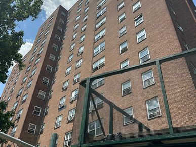 Tall brick apartment building under a partly cloudy sky.