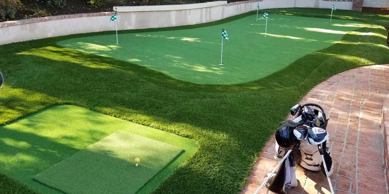 A backyard golf putting green with flags and golf clubs on a brick pathway.