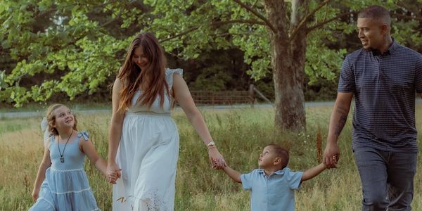 A family of four walking hand-in-hand in a grassy field.