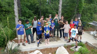 A group of kids and adults posing outdoors in nature.