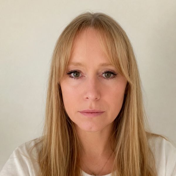 Close-up of a woman with long blonde hair and neutral expression.