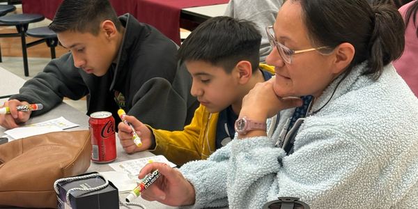 A teacher helping two students with their work.
