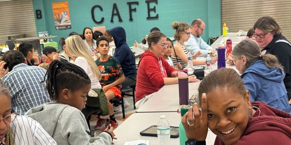 People gathered in a cafe setting, engaged in various activities.