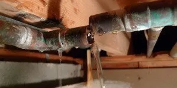 Leaking pipes with water dripping and flowing in a basement.