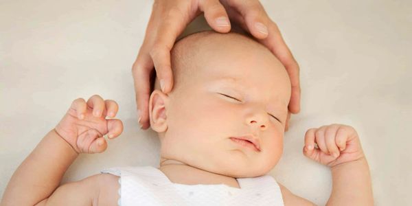 Sleeping baby with gentle hands cradling its head.