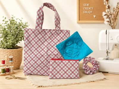 Photo of tote bag, zippered pouch, microwave bowl cozy and scrunchie amidst sewing machine and sewin