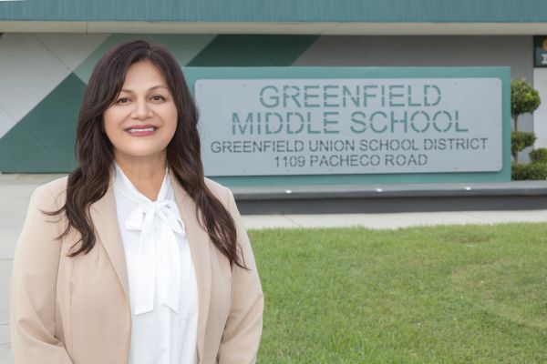 A woman stands smiling in front of Greenfield Middle School sign.