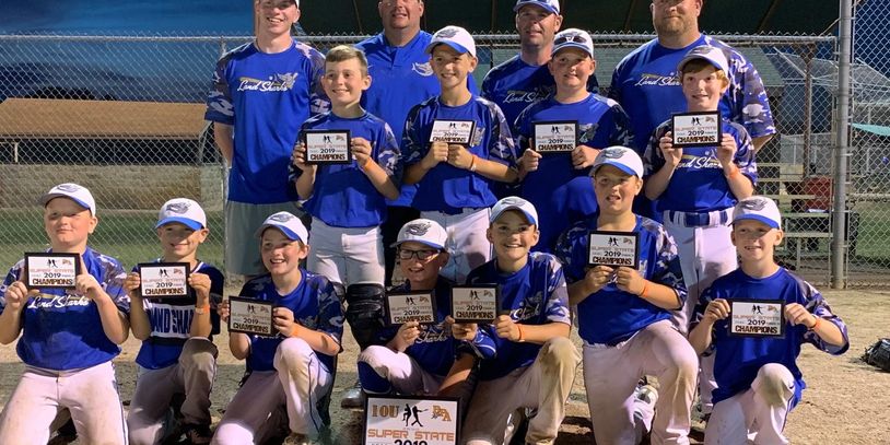 Youth baseball team proudly holding 2019 championship plaques.