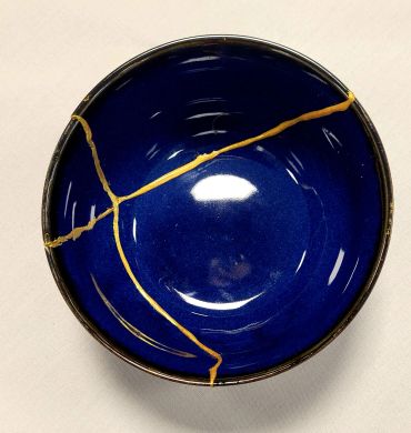 Blue bowl repaired with golden lacquer in kintsugi style.
