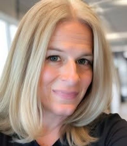 Smiling woman with blonde hair and blue eyes.