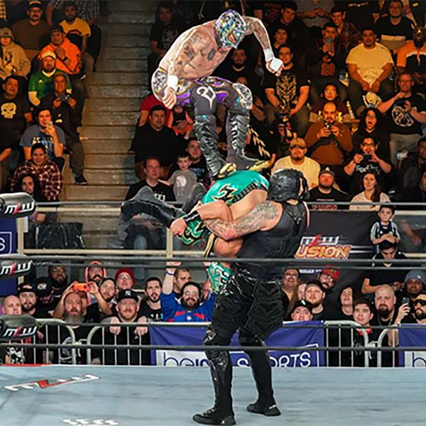 Photo of three wrestlers with masks performing a move in the ring