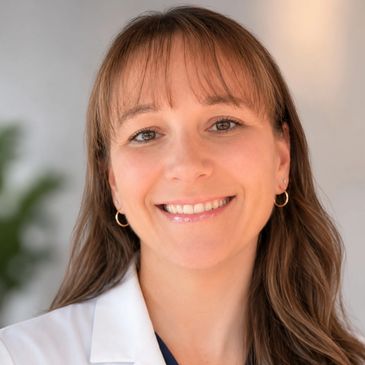 Smiling woman with long hair in a white coat.