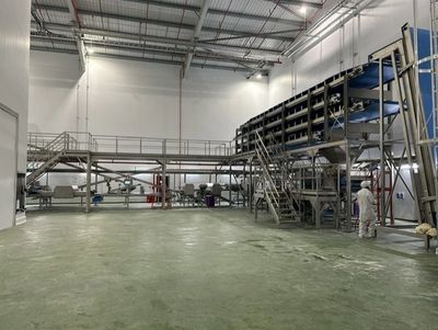 Industrial machinery inside a large factory with a worker in protective clothing.
