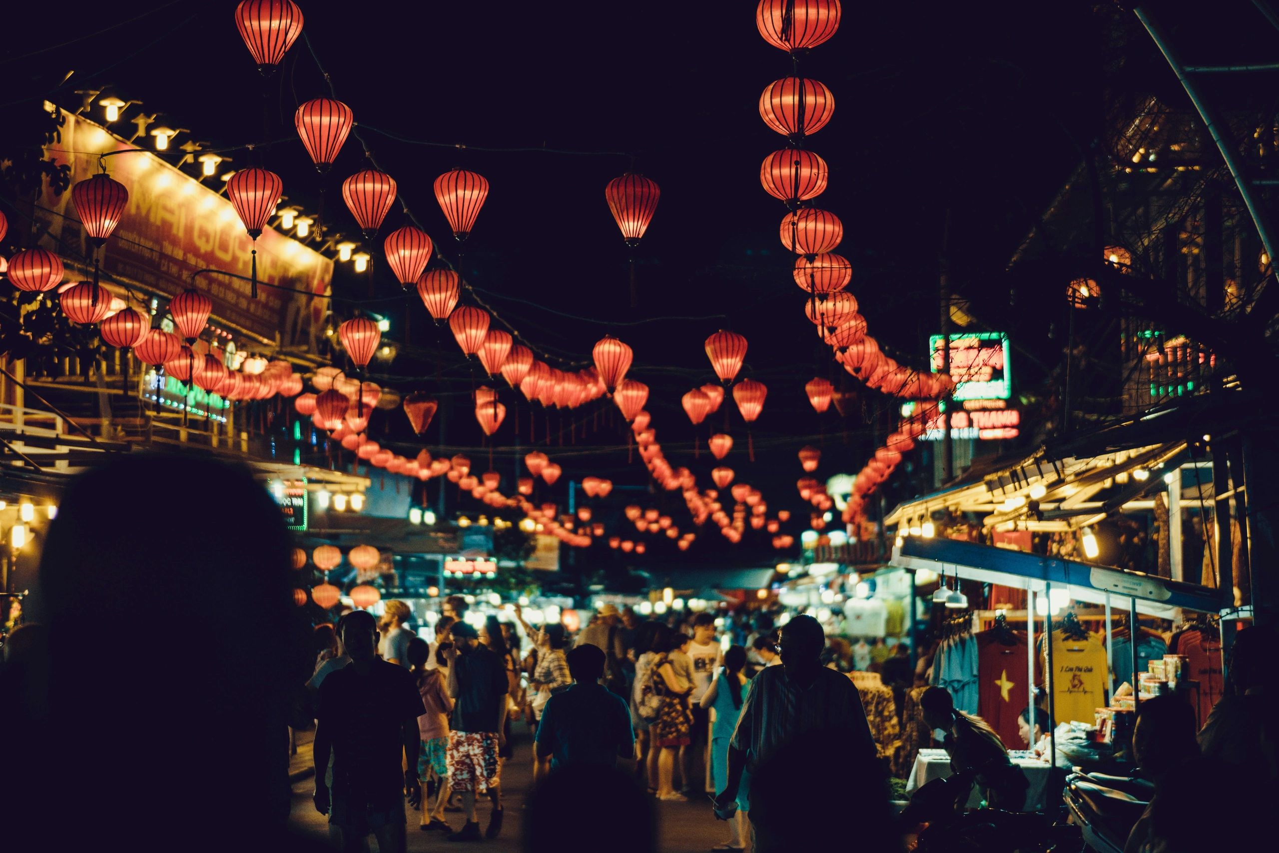 Night market bustling with people under glowing red lanterns.