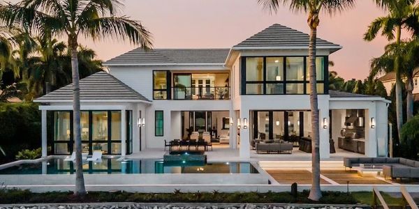 Modern luxury house with large windows and a pool at sunset.