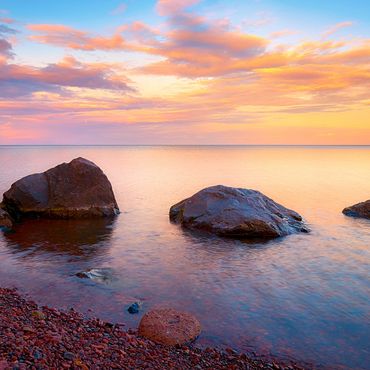 Sunset over red rocks in the waters of Lake Superior. Agates are often found on the shore.