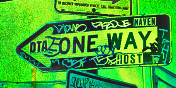Graffiti-covered one way street sign with vibrant green and yellow tones.