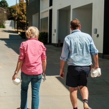 Senior couple walking holding white hats.