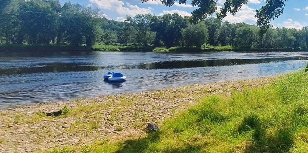 River with a small floating raft near a pebbled shore.