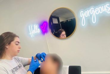 A woman wearing blue gloves administering an injection to a patient.