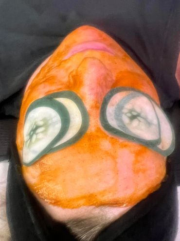 Person with face mask and cucumber slices on eyes lying down.