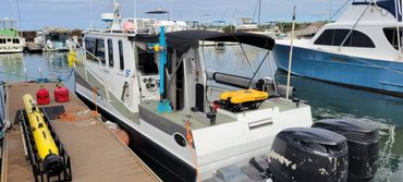 A white research boat docked at a marina with equipment on board.
