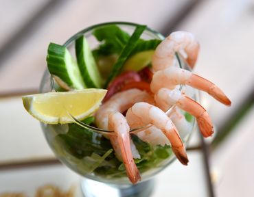 A shrimp cocktail with lemon and cucumber slices in a glass.