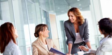 A woman leading a business meeting with three colleagues in an office.