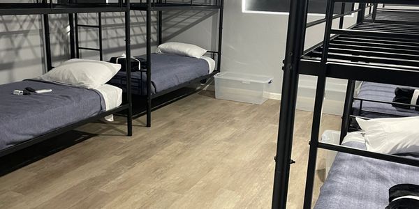 A clean dormitory room with multiple bunk beds and neatly made beds.