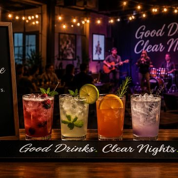 Colorful cocktails on a bar with live music in the background.