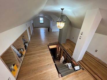 Renovated attic space with wooden flooring and storage cubbies along the wall.