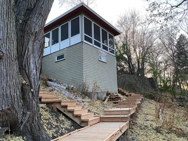 Wooden stairs leading to a small elevated building on a hillside.