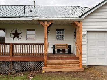 Cozy porch with wooden bench and star wall decoration on a house with metal roof.