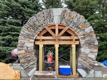 Stone arch under construction with wooden supports and tools around.